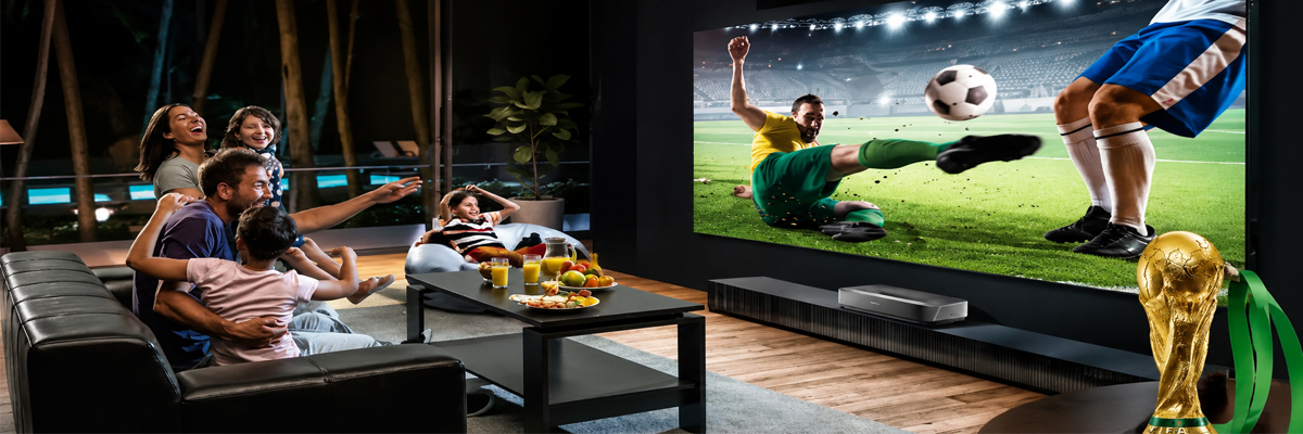 A group of football fans watching a live World Cup match on a large, high-definition indoor LED screen inside a modern living room or lounge